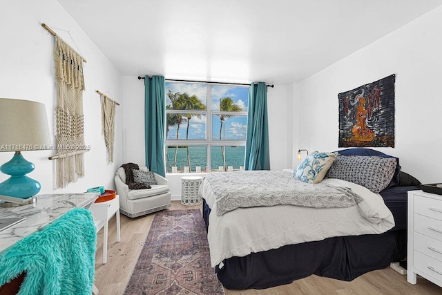 bedroom with a water view and light hardwood / wood-style floors