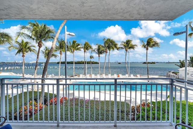 view of swimming pool featuring a water view and a view of the beach