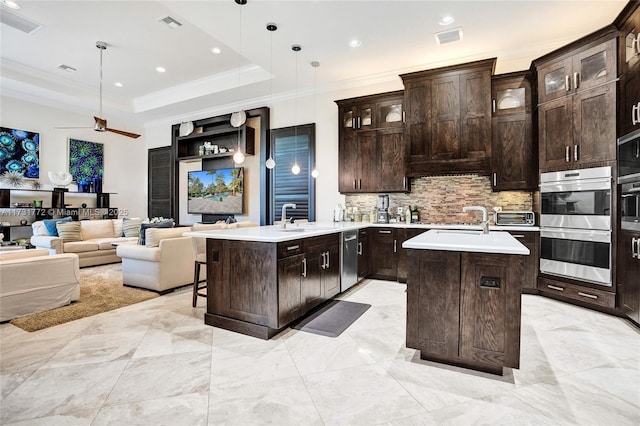 kitchen featuring an island with sink, dark brown cabinets, and decorative light fixtures