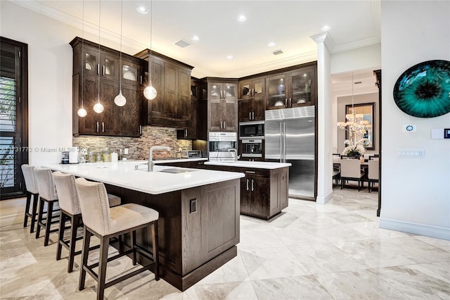 kitchen with sink, built in appliances, hanging light fixtures, dark brown cabinets, and kitchen peninsula