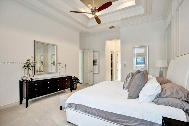 bedroom featuring light carpet, ornamental molding, a tray ceiling, ceiling fan, and a high ceiling