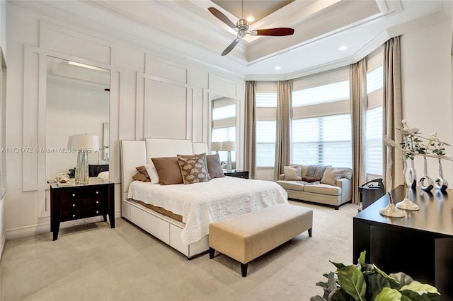 bedroom featuring ornamental molding, light carpet, ceiling fan, and a tray ceiling