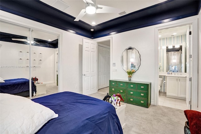 bedroom featuring connected bathroom, sink, light colored carpet, a closet, and ceiling fan