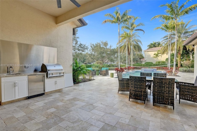 view of patio with ceiling fan, an outdoor kitchen, sink, and area for grilling