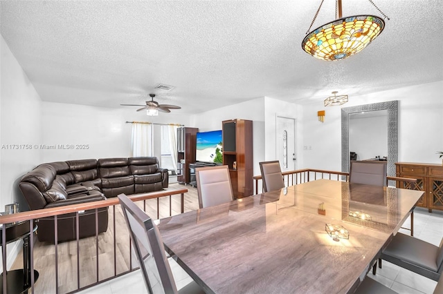 dining space with ceiling fan, light tile patterned floors, and a textured ceiling