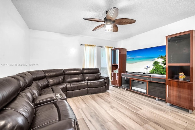 living room featuring ceiling fan, a textured ceiling, and light hardwood / wood-style floors