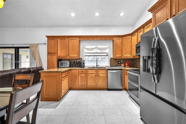 kitchen featuring backsplash, stainless steel appliances, sink, and stone counters