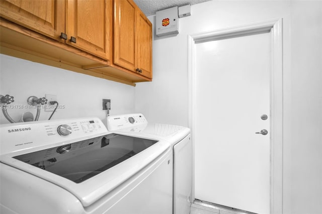 laundry area featuring cabinets, light tile patterned flooring, washing machine and clothes dryer, and a textured ceiling