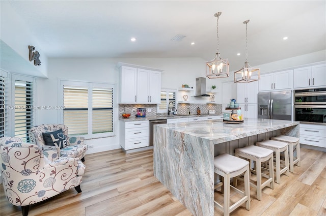 kitchen featuring visible vents, a kitchen island, tasteful backsplash, vaulted ceiling, and stainless steel appliances