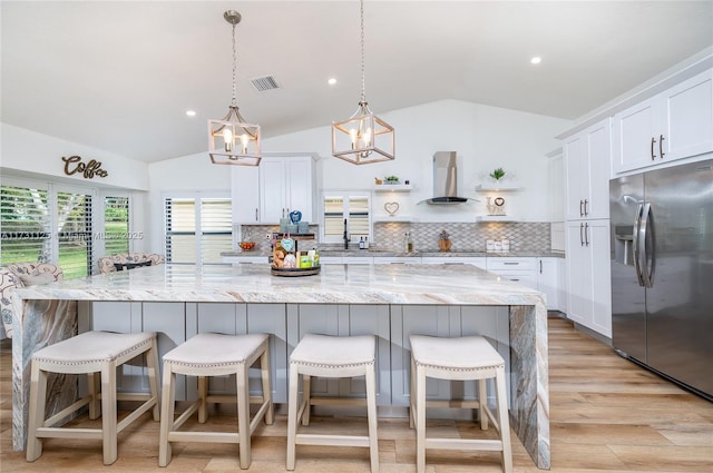 kitchen with lofted ceiling, a large island, stainless steel fridge with ice dispenser, and white cabinets