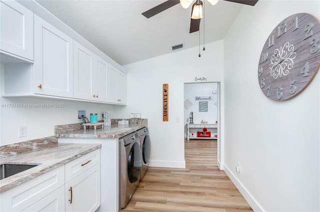 clothes washing area featuring washer and dryer, cabinet space, ceiling fan, light wood-type flooring, and visible vents