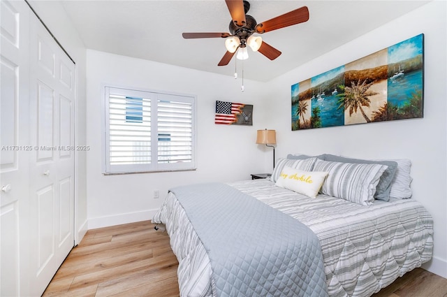 bedroom featuring light wood-style floors, baseboards, ceiling fan, and a closet