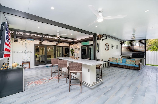 kitchen with ceiling fan, a kitchen bar, and light hardwood / wood-style floors