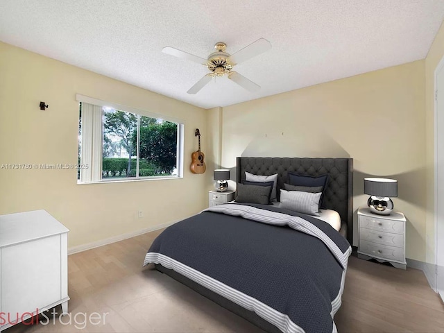 bedroom with hardwood / wood-style floors, a textured ceiling, and ceiling fan