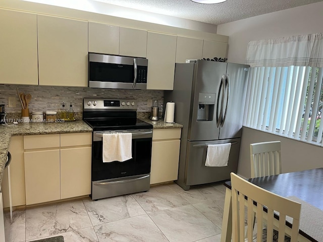 kitchen with tasteful backsplash, stainless steel appliances, and cream cabinets