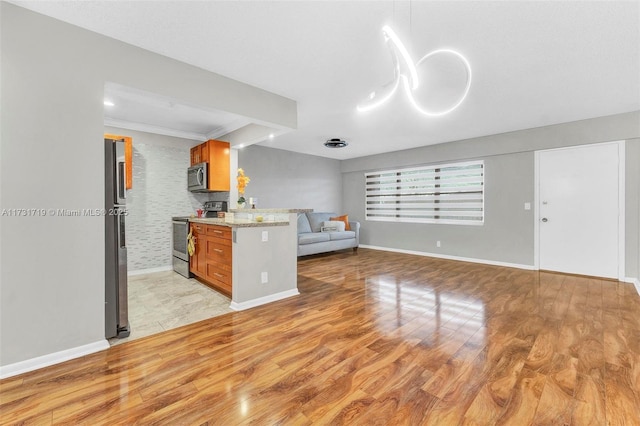 kitchen featuring light stone counters, appliances with stainless steel finishes, kitchen peninsula, and light hardwood / wood-style flooring