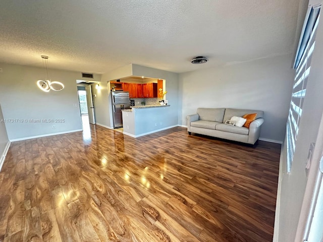 unfurnished living room featuring dark hardwood / wood-style flooring, a textured ceiling, and an inviting chandelier