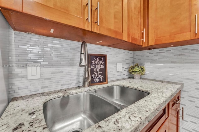 interior details featuring sink, backsplash, and light stone counters