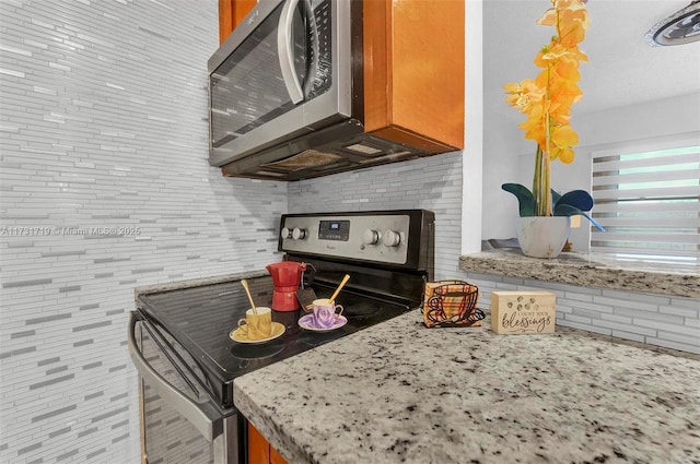 kitchen with stainless steel appliances, tasteful backsplash, and light stone countertops