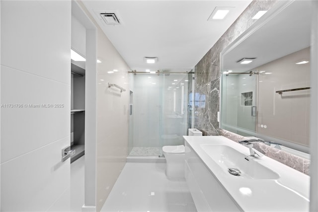 bathroom featuring vanity, a shower with shower door, tile walls, and toilet