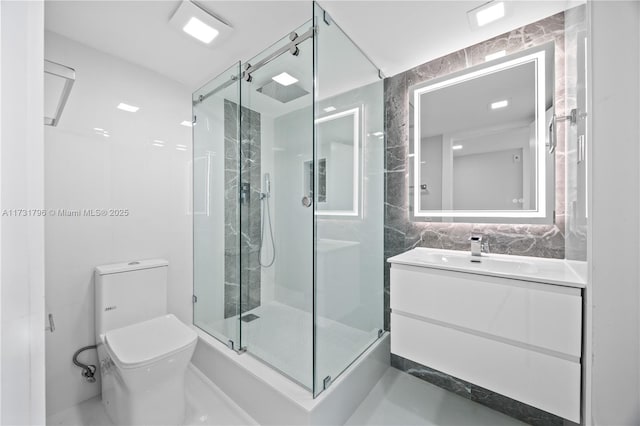 bathroom with toilet, tile walls, vanity, a shower with door, and decorative backsplash