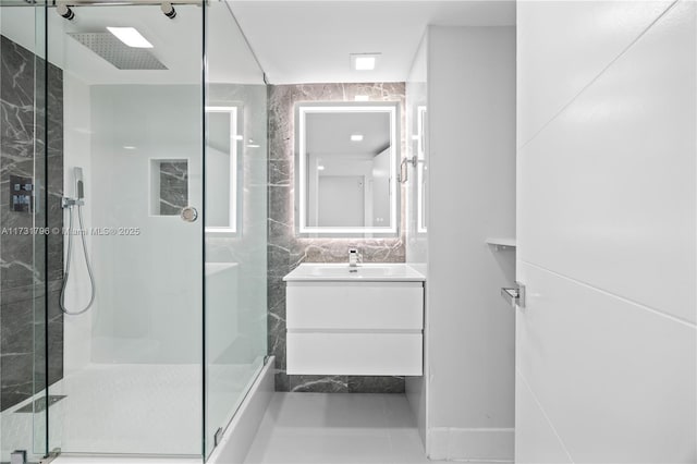 bathroom with vanity, a shower with shower door, and tile walls