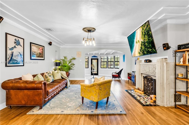 living room featuring wood-type flooring, ornamental molding, and an inviting chandelier