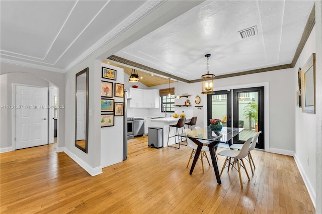 dining space with light hardwood / wood-style flooring, ornamental molding, and a raised ceiling