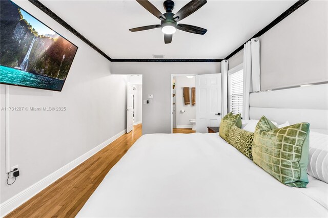 bedroom featuring ceiling fan, ensuite bath, wood-type flooring, and crown molding