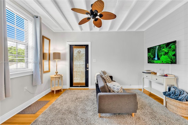 living room with ceiling fan, plenty of natural light, hardwood / wood-style floors, and beam ceiling