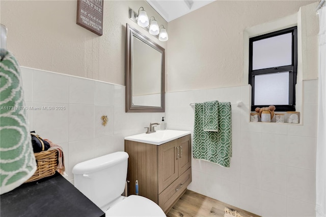 bathroom with hardwood / wood-style floors, vanity, tile walls, and toilet