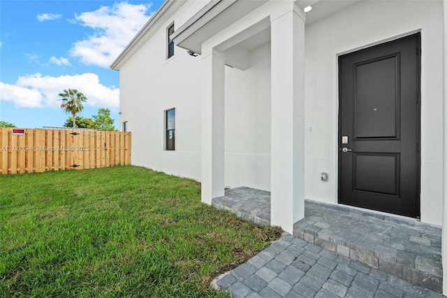 view of exterior entry featuring a lawn