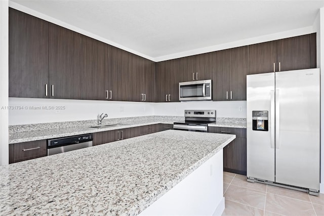 kitchen featuring light stone counters, stainless steel appliances, sink, and dark brown cabinets