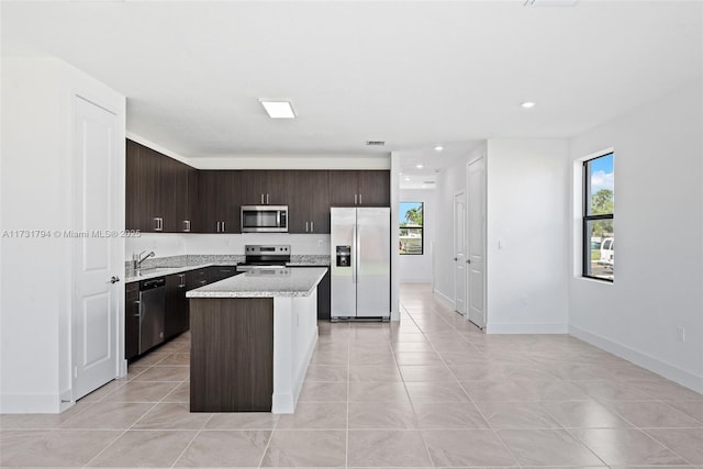 kitchen featuring sink, a center island, light tile patterned floors, dark brown cabinetry, and stainless steel appliances