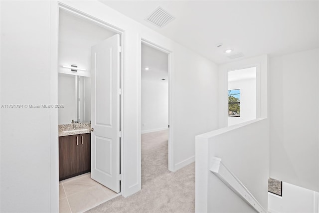 hall with sink and light colored carpet