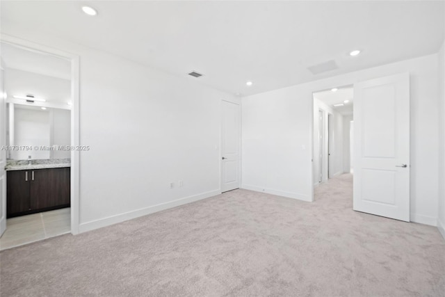 unfurnished bedroom featuring light colored carpet and connected bathroom