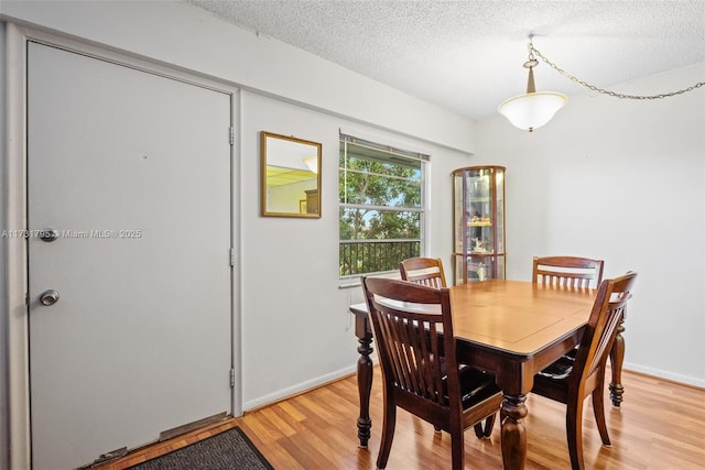 dining area with a textured ceiling and light hardwood / wood-style floors