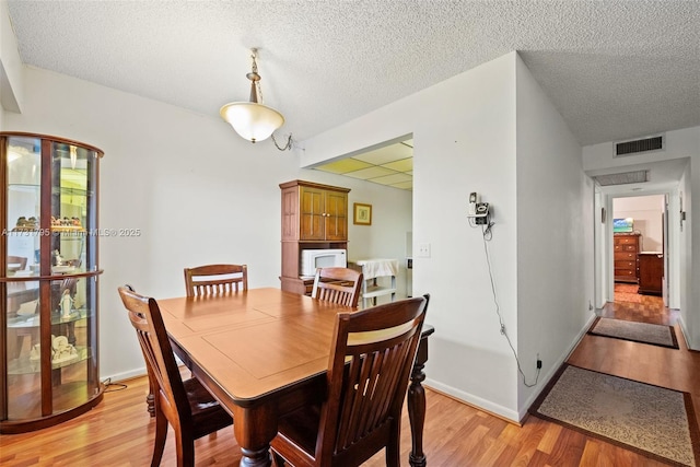 dining room with a textured ceiling and light wood-type flooring