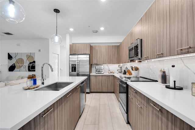 kitchen with tasteful backsplash, sink, decorative light fixtures, and stainless steel appliances