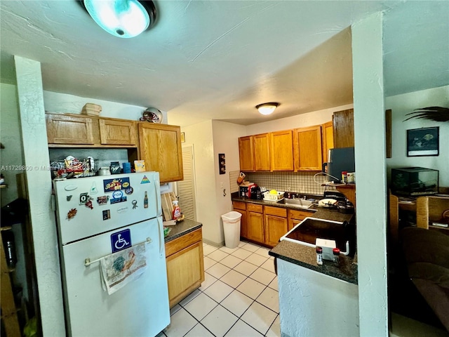 kitchen with tasteful backsplash, light tile patterned floors, sink, and white refrigerator