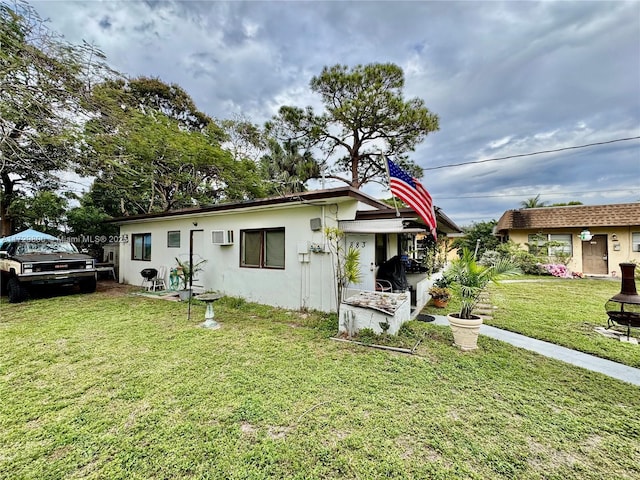 view of front of house featuring a wall mounted AC and a front lawn