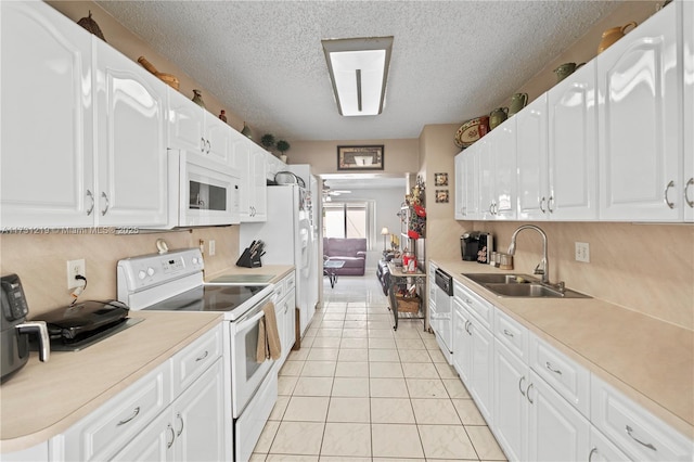 kitchen featuring sink, white cabinetry, a textured ceiling, light tile patterned floors, and white appliances