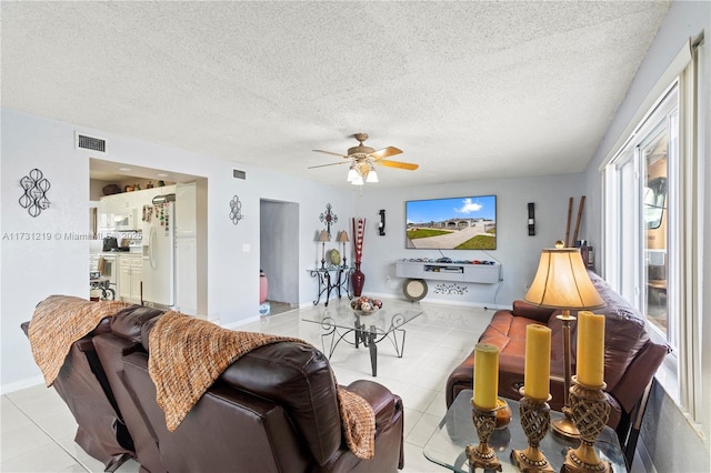 living room featuring ceiling fan, light tile patterned floors, and a textured ceiling