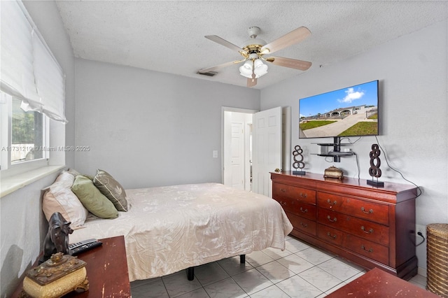 bedroom featuring light tile patterned floors, a textured ceiling, and ceiling fan