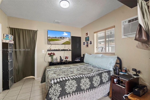 tiled bedroom featuring a wall mounted air conditioner and a textured ceiling