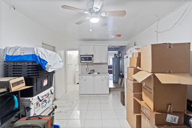 kitchen with stainless steel microwave, white cabinets, backsplash, light tile patterned floors, and ceiling fan