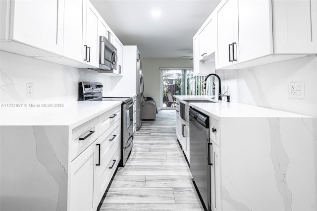 kitchen featuring white cabinetry, appliances with stainless steel finishes, light countertops, and backsplash