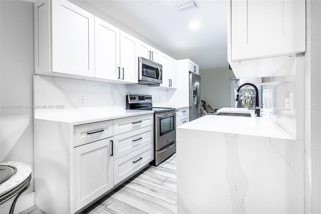 kitchen featuring stainless steel appliances, visible vents, backsplash, white cabinetry, and a sink