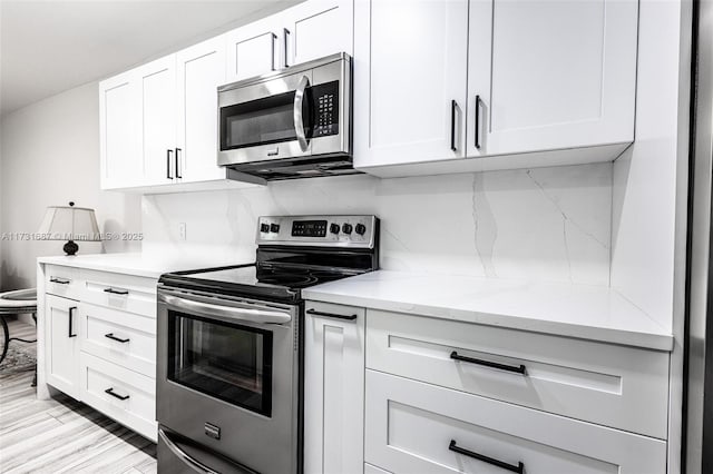 kitchen with stainless steel appliances, light stone countertops, light hardwood / wood-style flooring, and white cabinets