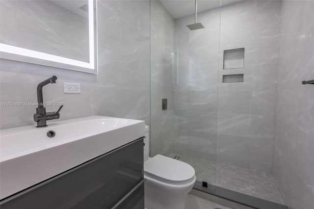 bathroom with vanity, toilet, tile walls, and a tile shower